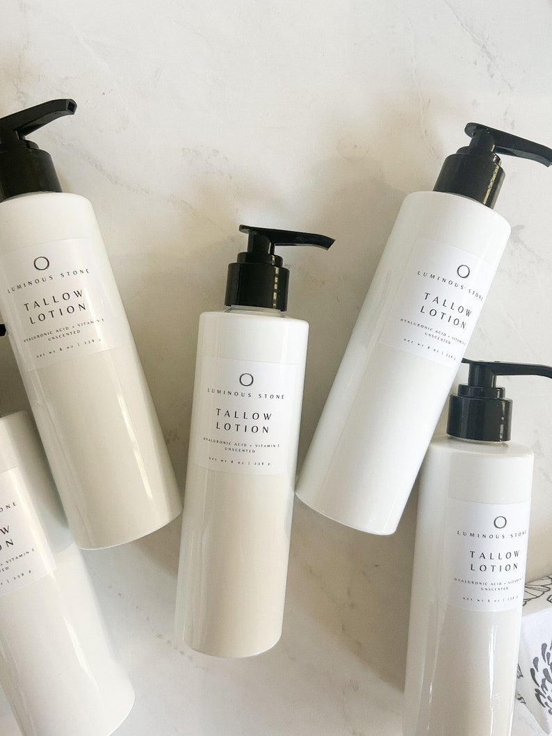 May include: Four white bottles of unscented tallow lotion with black pump tops. The bottles are labeled "LUMINOUS STONE TALLOW LOTION HYALURONIC ACID + VITAMIN E UNSCENTED NET WT 8 OZ / 236 g"