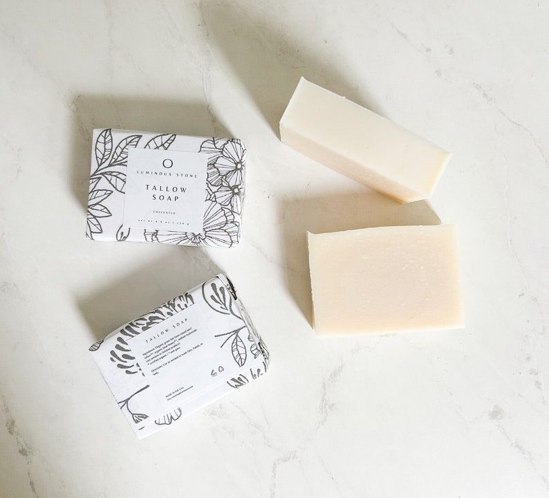 Puede incluir: Dos barras de jab&oacute;n de sebo blanco con un dise&ntilde;o floral en el empaque. El empaque dice "Luminous Stone Tallow Soap, Organic".