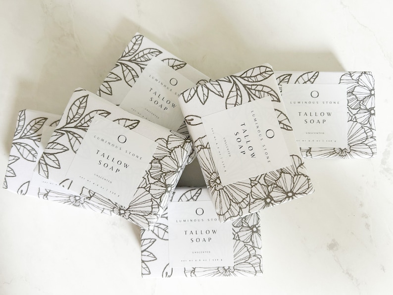 Puede incluir: Cinco barras de jab&oacute;n blanco con dise&ntilde;os florales negros y el texto "Luminous Stone Tallow Soap Unscented" en cada barra.