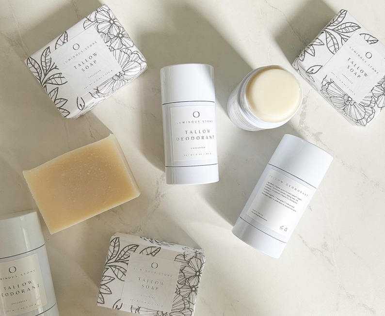 Puede incluir: Una vista plana de varios productos de belleza naturales de Luminous Stone. Los productos incluyen una barra de jab&oacute;n de sebo, un desodorante en barra y una caja de jab&oacute;n de sebo. Los productos son todos blancos y tienen texto negro. El fondo es una superficie de m&aacute;rmol blanco.