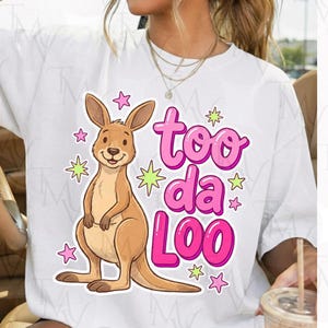 Op de afbeelding: Wit T-shirt met een cartoon kangoeroe en de tekst "too da loo" in roze. De kangoeroe is bruin, lacht en is omringd door roze sterren en groene sterren. Een leuk, casual ontwerp.