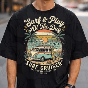 Peut inclure: T-shirt noir avec un motif de surf rétro. Le graphisme représente un van, une planche de surf et des palmiers, avec le texte "Surf & Play All The Day" et "Surf Cruiser California Coastline Est. 1971". Le design a une ambiance vintage et plage.