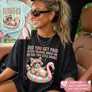 Peut inclure: T-shirt noir avec le texte "DID YOU GET PAID AFTER TALKING ABOUT ME OR ARE YOU STILL BROKE." Le motif représente un raton laveur portant des lunettes de soleil en forme de cœur, tenant une boisson et flottant sur un flotteur en forme de flamant rose.