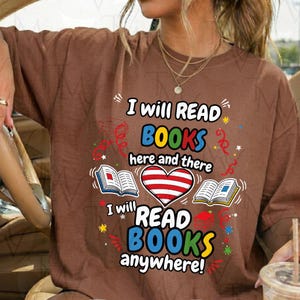 Peut inclure: Un t-shirt marron avec le texte I will READ BOOKS here and there I will READ BOOKS anywhere accompagné d'illustrations de deux livres ouverts, d'un cœur rayé rouge et blanc et de confettis colorés imprimés sur le devant.