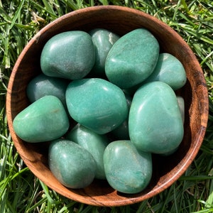 Può includere: Una ciotola di pietre di aventurina verde rotolata. Le pietre sono lisce e levigate e hanno un colore verde chiaro.