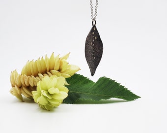 leaf-shaped silver pendant with diamonds