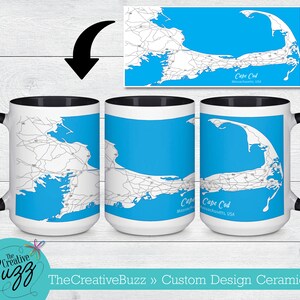 May include: A white ceramic mug with a black rim and handle. The mug features a map of Cape Cod, Massachusetts, USA, printed on the front. The map is in black and white with blue water.