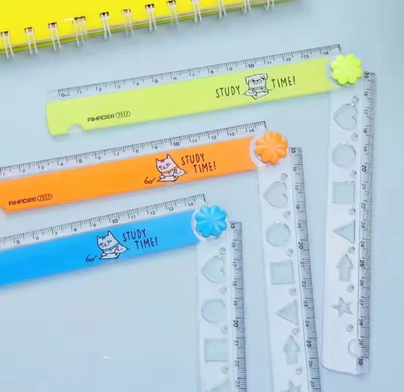 May include: Three folding rulers in neon yellow, orange, and blue, each featuring a cartoon animal illustration and the text "STUDY TIME!". The rulers have a flower-shaped hinge and a clear plastic extension with various geometric cutouts.