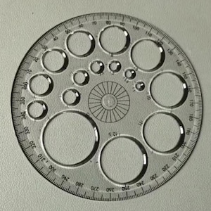 May include: A clear plastic protractor with multiple circular cutouts of varying sizes. The protractor has degree markings from 0 to 360 and a central design. It is a tool used for measuring angles and drawing circles.