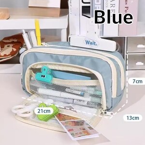 May include: A light blue pencil case with a cream-colored zipper and trim, featuring a mesh interior pocket, a white clip labeled "Wait.", and stationery items. The case measures 21 cm in length, 13 cm in height, and 7 cm in width.