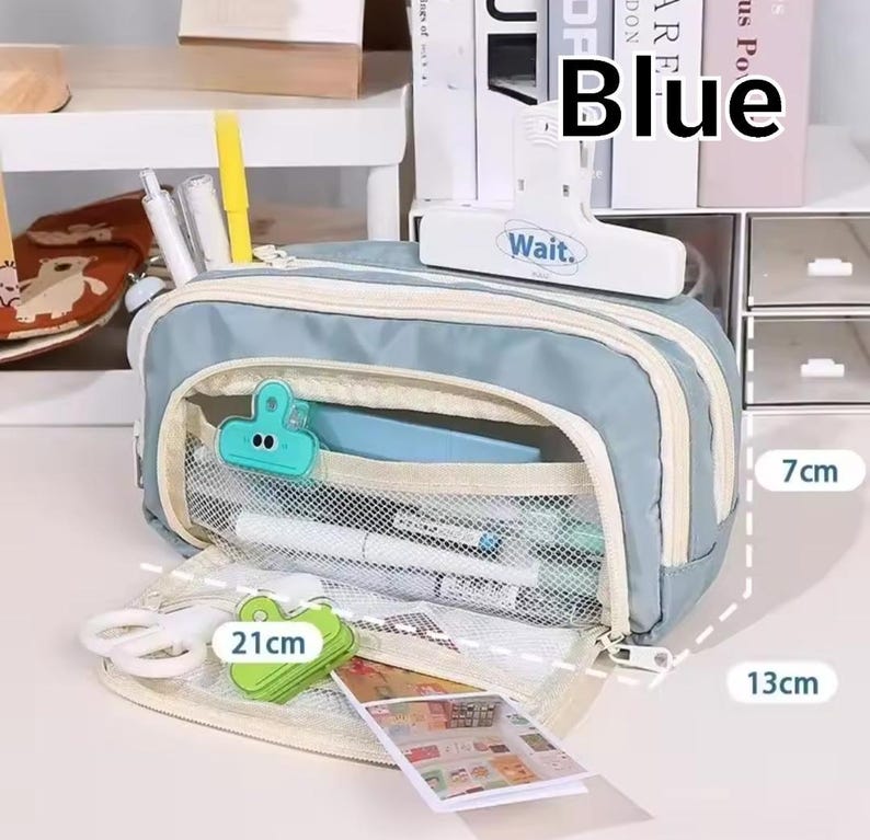May include: A light blue pencil case with a cream-colored zipper and trim, featuring a mesh interior pocket, a white clip labeled "Wait.", and stationery items. The case measures 21 cm in length, 13 cm in height, and 7 cm in width.