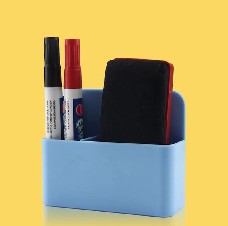 May include: A light blue desk organizer with a black marker, a red marker, and a black eraser. The organizer has three compartments. The markers have white labels with black text. The eraser has a red frame.