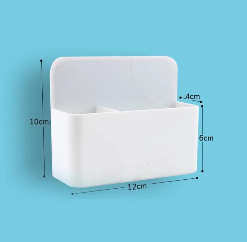 May include: A white plastic wall-mounted organizer with two compartments. The organizer is 12 cm wide, 10 cm tall, and 4 cm deep. It is designed to hold small items and has a simple, clean design.