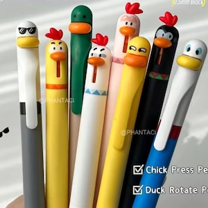 Peut inclure: Une collection de stylos fantaisie avec des motifs de canards et de poulets de dessin animé. Les stylos sont de différentes couleurs, dont le jaune, le blanc, le noir et le vert, avec des détails de crête rouge. Les stylos ont une pointe d'encre noire de 0,5 mm et sont étiquetés "Chick Press Pen" et "Duck Rotate Pen."