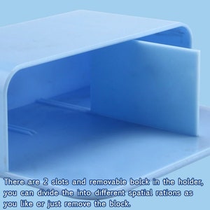 May include: A light blue plastic organizer with a removable divider. The organizer has two slots and a flat base. The text on the image says, "There are 2 slots and removable block in the holder, you can divide the into different spatial rations as you like or just remove the block."
