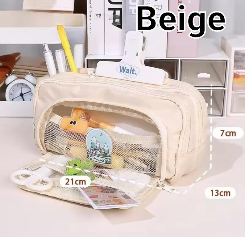 May include: A beige pencil case with a zipper closure, featuring a white clip labeled "Wait." on top. The interior has mesh pockets containing stationery items. Dimensions are clearly marked as 21cm in length, 7cm in height, and 13cm in width.