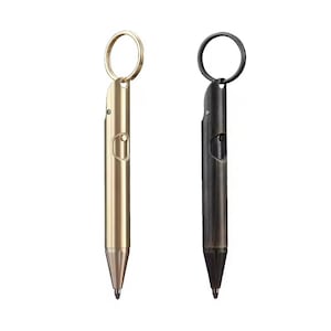 Könnte beinhalten: Zwei Metallstifte mit Schlüsselringen. Ein Stift ist goldfarben, der andere dunkelgrau. Beide Stifte haben ein ähnliches Design mit rundem Körper und spitzer Spitze. Die Stifte sind kompakt und tragbar.