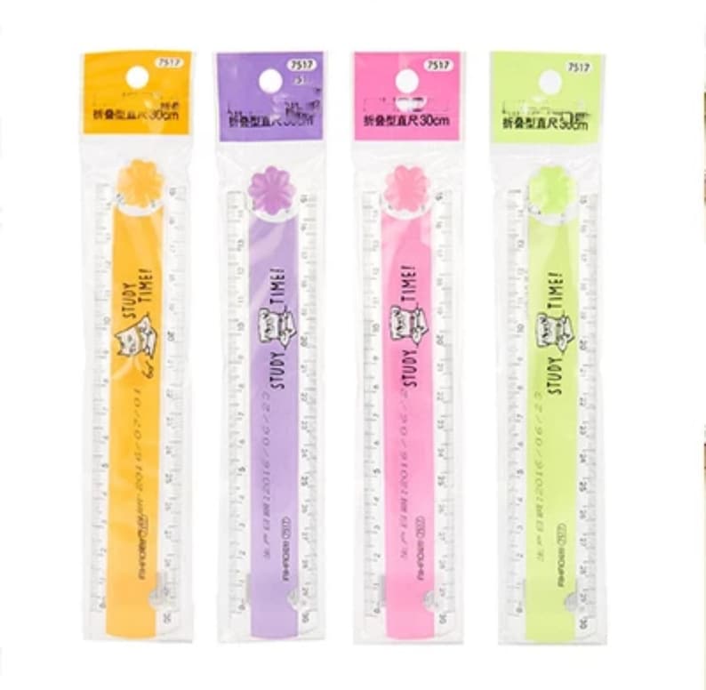 May include: Four 30 cm folding rulers in yellow, purple, pink, and light green, each packaged in a clear plastic sleeve. Each ruler features a flower-shaped hinge, a cat illustration, and the text STUDY TIME printed on the front surface.