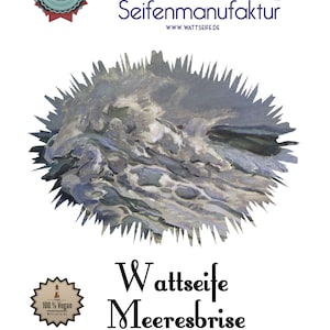 Op de afbeelding: Een wit label met blauwe en zwarte tekst voor een zeep product genaamd "Wattseife Meeresbrise" gemaakt met zeewier. Het label toont een blauwe en witte illustratie van een zeegolf en de tekst "Dangaster Seifenmanufaktur" met de website www.wattseife.de. Het label bevat ook twee ronde logo's, een met de tekst "Seife aus Dangast" en de andere met de tekst "100% Vegan Wattseife.de".