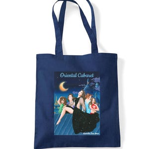 Peut inclure: Sac fourre-tout bleu marine avec une illustration de cabaret et le texte "Oriental Cabaret". L'œuvre représente des femmes sur un balcon avec un croissant de lune et une ligne d'horizon urbaine. Le sac a deux anses bleu marine.