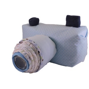 May include: A blue and white camera-shaped baby shower gift basket filled with baby clothes and other essentials.
