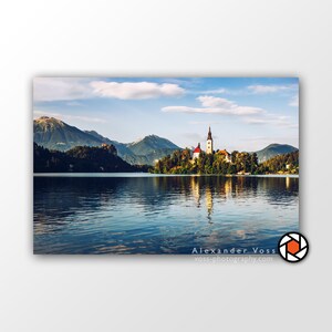 Pode incluir: Uma vista pitoresca de uma igreja em uma pequena ilha em um lago, cercada por montanhas. A água está calma e reflete o céu e a igreja.