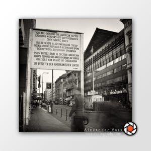 Könnte beinhalten: Ein Schwarzweißfoto eines Schildes in Berlin, Deutschland, auf dem steht "Sie betreten den amerikanischen Sektor. Waffen ausser Dienst verboten. Befolgen Sie die Verkehrsregeln." Das Schild steht vor einem Gebäude mit einem McDonald's-Schild.