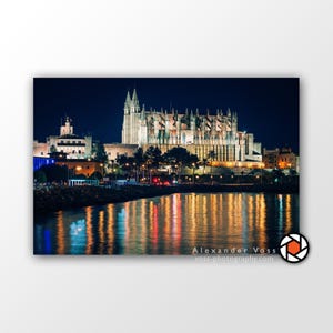 Peut inclure: Vue nocturne d'une grande cathédrale illuminée avec son reflet dans l'eau. La cathédrale est de couleur beige clair avec une haute flèche pointue. L'eau est bleu foncé et reflète les lumières de la ville.