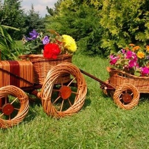 May include: A wicker tractor and wagon with colorful flowers in the baskets. The tractor has a brown and red body and large wicker wheels. The wagon has a brown wicker body and smaller wicker wheels.
