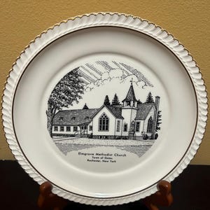 May include: A white ceramic plate with a gold rim features a black and white illustration of Elmgrove Methodist Church in the Town of Gates, Rochester, New York.