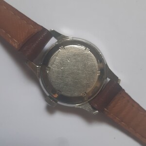 K&ouml;nnte beinhalten: R&uuml;ckansicht einer silbernen Armbanduhr mit einem braunen Lederarmband. Das Zifferblatt der Uhr ist nicht sichtbar.