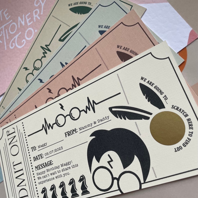 May include: A cream-colored ticket with black text and graphics. The ticket says "ADMIT ONE" and has a message that says "Happy Birthday Maggy! We can't wait to share this experience with you." The ticket also has a scratch-off area with a gold circle.