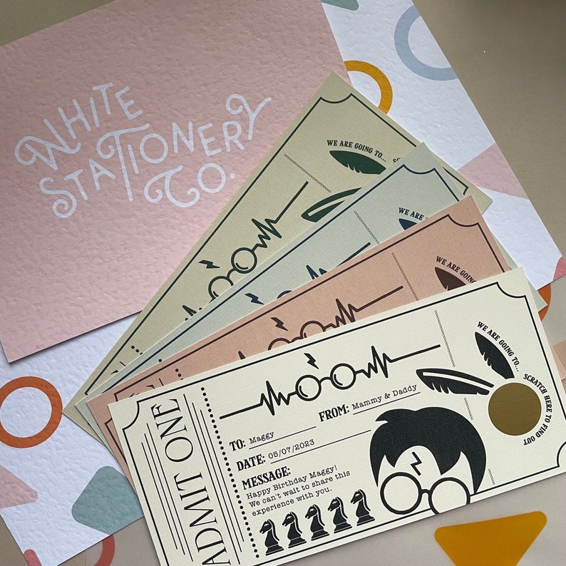 May include: A Harry Potter themed birthday party ticket with a gold scratch-off area. The ticket says "We are going to..." and has a heart beat line with glasses and a feather. The ticket is for Maggy's birthday on 08/07/2023. The ticket is from Mammy & Daddy.