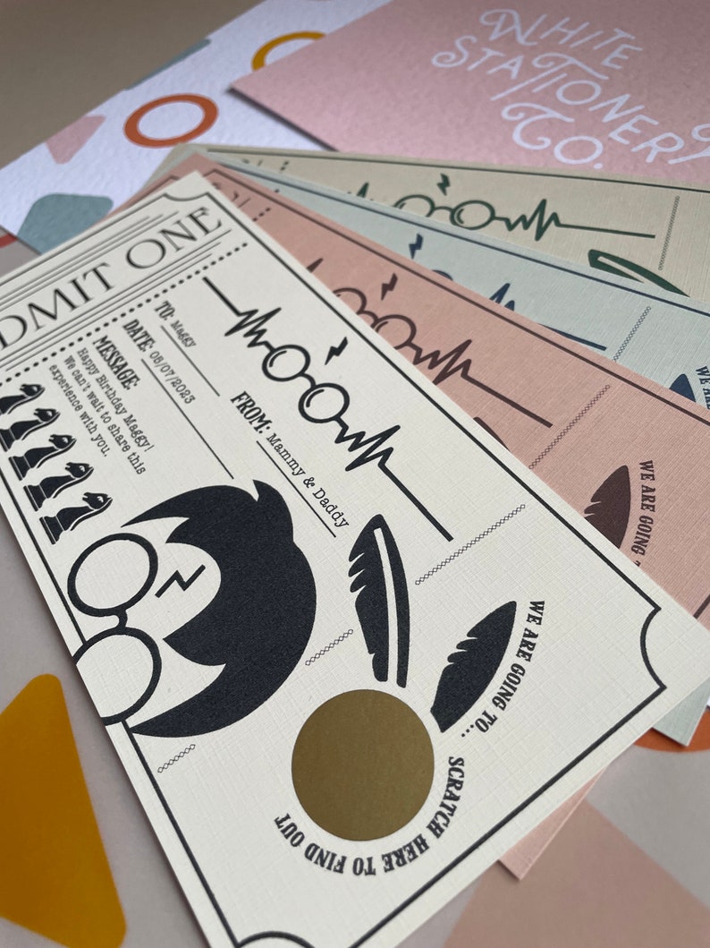 May include: A white card with a gold scratch-off area. The card has a black and white illustration of Harry Potter's glasses and a feather. The text on the card reads "Admit One", "To: Maggy", "Date: 05/07/2023", "Message: Happy Birthday Maggy! We can't wait to share this experience with you.", "From: Mammy & Daddy", "We are going to... Scratch here to find out".