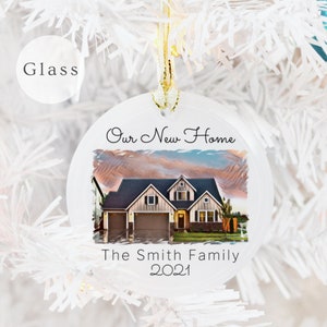 May include: White round glass ornament with a picture of a house and the text "Our New Home The Smith Family 2021".