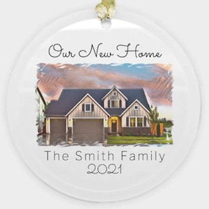May include: A white round Christmas ornament with a watercolor image of a house with a mountain range in the background. The text "Our New Home The Smith Family 2021" is printed on the ornament.