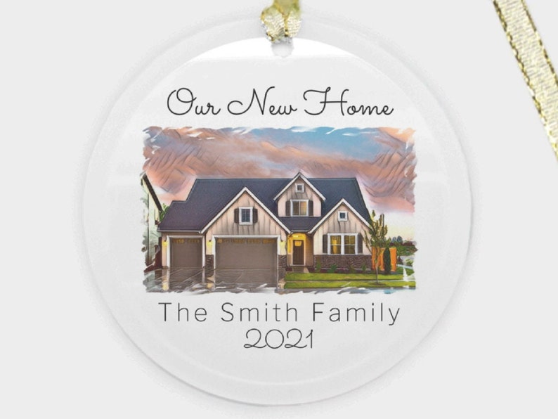May include: A white round Christmas ornament with a watercolor image of a house with a mountain range in the background. The text "Our New Home The Smith Family 2021" is printed on the ornament.
