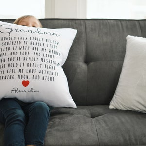 May include: White pillow with black text that reads "Grandma I hugged this little pillow I squeezed it really tight I filled it with all my wishes hope, and love, and light So when you're really missing just hold it really tight You'll feel my love within it morning, noon, and night Alexandra" with a red heart symbol.