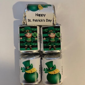 May include: Four small chocolate bars wrapped in silver foil with green and white labels. The labels feature a cartoon leprechaun and the text "Happy St. Patrick's Day".