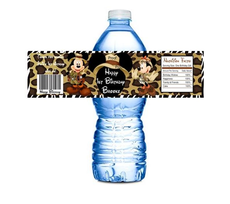 May include: Water bottle label with a jungle animal print background. The label features a cartoon image of Mickey Mouse and Minnie Mouse dressed in safari outfits. The text on the label reads "Happy 1st Birthday Brooke".