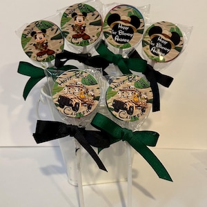 May include: A set of six lollipop favors with green and black ribbon bows. The lollipops feature round, printed edible images of Mickey Mouse in a safari outfit, and a safari jeep with Mickey Mouse and friends. The text on the lollipops reads "Happy Birthday Carter" and "Happy 1st Birthday Andrew".