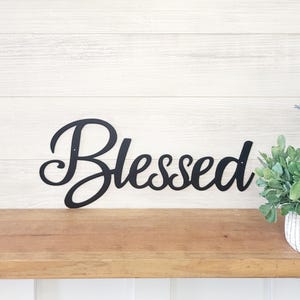 May include: Black metal wall decor with the word "Blessed" in a cursive font.
