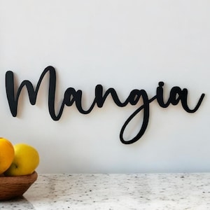 May include: Black wooden sign with the word "Mangia" written in cursive script.