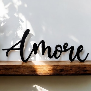 May include: Black wooden sign with the word "Amore" written in a cursive font.