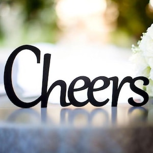 May include: Black wooden sign with the word "Cheers" in a cursive font.