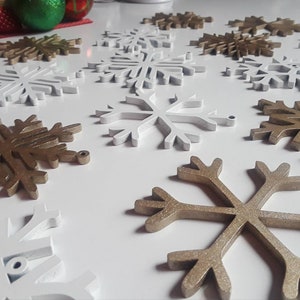 May include: A collection of white and gold snowflake ornaments. The snowflakes are made of wood and have a rustic, vintage look. They are perfect for adding a touch of winter charm to your home decor.