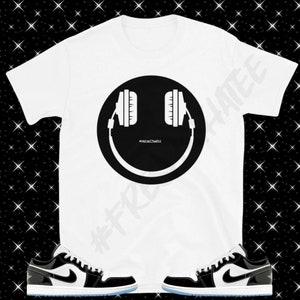 May include: White t-shirt with a black smiley face wearing headphones. The text "#hypebeastlife" is inside the smiley face.  The t-shirt is paired with black and white sneakers with a blue outsole.