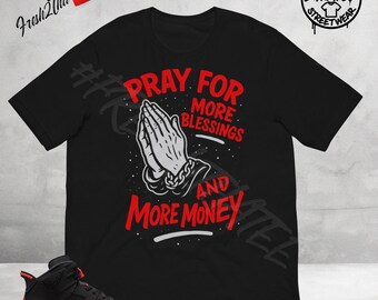 Camiseta "Ora por más bendiciones y más dinero" hecha a juego con las zapatillas Jordan 6 SALESMAN con infrarrojos inversos, color rojo y negro.