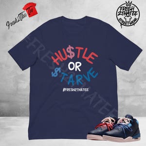 May include: A navy blue short-sleeve t-shirt featuring the text HUSTLE OR STARVE in red, white, and blue, with a dollar sign replacing the S in HUSTLE and STARVE. The text #FRESH2THATEE is printed below in white. A pair of navy and light blue sneakers.