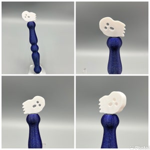 May include: Four white ghost-shaped bottle stoppers with blue bases. The ghosts have three holes for eyes and a mouth. The bases are a dark blue color with a speckled texture.